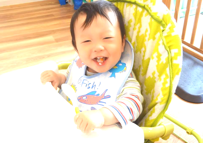 笑顔の赤ちゃんがご飯を食べている