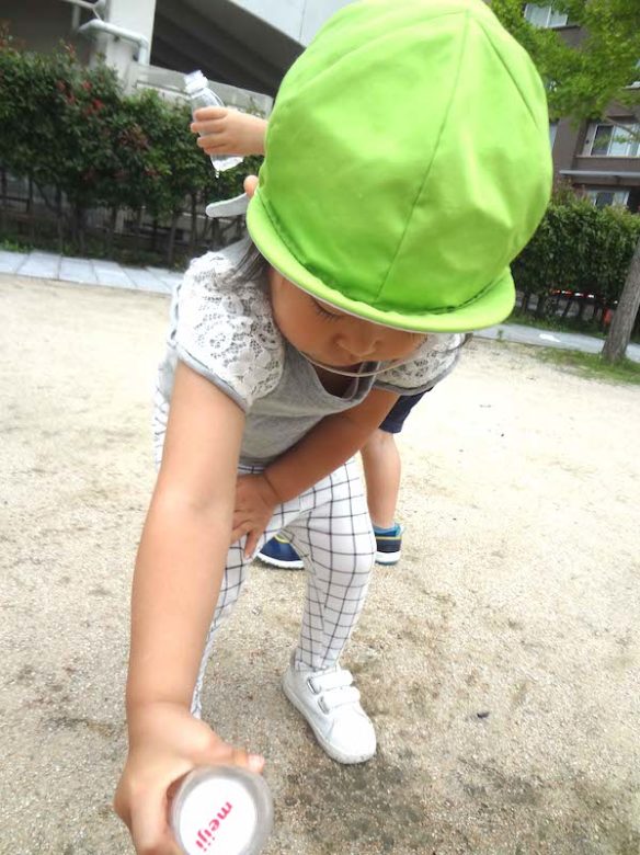お外で子どもたちがペットボトルを持って水遊びをしている