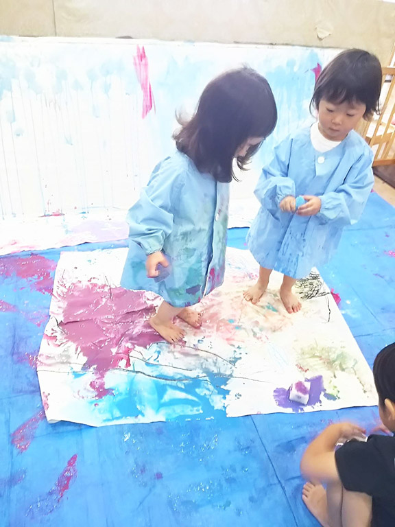 足の裏を使って絵の具でペイントする子ども
