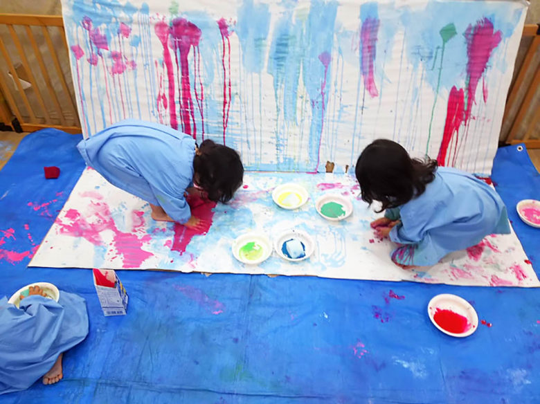 手足を使って絵の具遊びをする子どもたち